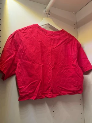 Röd croppad t-shirt - En enkel röd croppad t-shirt med rund hals och korta ärmar. Perfekt till höga jeans eller kjol för en avslappnad look. Tillverkad i mjuk bomull som känns skön mot huden.