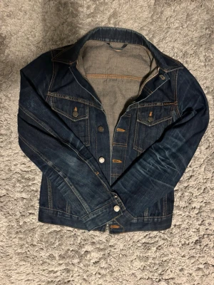 Selvedge jeansjacka från Nudie jeans  - Säljer en asfet jeans jacka från Nudie jeans. Modell Perry och färg organic dry selvedge/selvage. Sjuka fades på den och fade Journey startad 2013 vilket finns nedskrivet i jackan. Bra skick, använd men kan inte hitta några defekter. Storlek XS, hör av dig vid frågor!