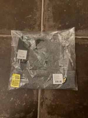 Lyle scott mössa - Snygg grå ribbstickad mössa från Lyle scott med klassiska loggan broderad framtill. Mössan har uppvikt kant och är tillverkad i mjukt material som håller dig varm. Perfekt accessoar för kyliga dagar och enkel att matcha med olika outfits. Tveka inte med att ställa frågor!