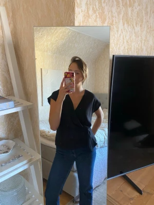 Zara topp - Svart blus/ topp från Zara som går omlott och har ett knyte vid sidan. Aldrig använd med lappen kvar, nypris 200kr under rean