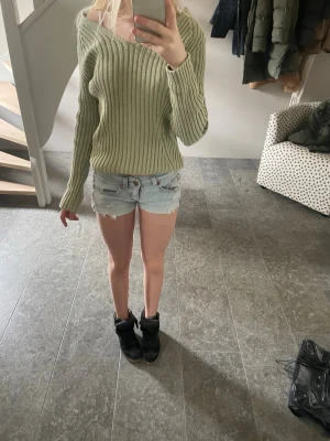 Ljusgrön ribbstickad tröja  - Trendig ljusgrön ribbstickad tröja från SIS by Sisters. Tröjan har en avslappnad passform, v-ringad hals och långa ärmar. Perfekt att styla med jeans eller kjol för en cool vardagslook.