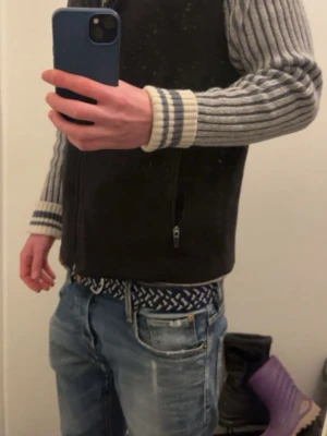 Ull hoodie med dragkedja - Säljer en gråmelerad hoodie från jack and jones vintage med hel dragkedja, två fickor fram och ribbade muddar i vitt och grått. Ärmarna har ett randigt mönster och luvan är fodrad. Perfekt för dig som gillar en avslappnad men snygg stil.