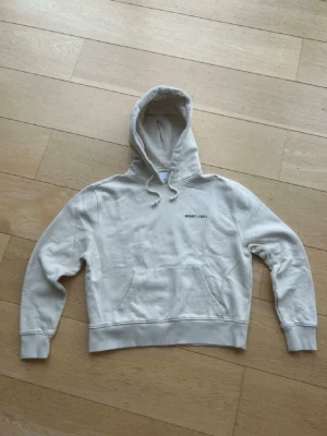 Beige  hoodie från Axel Arigato - Säljer en stilren beige hoodie från Axel Arigato med tryck fram och stort tryck på ryggen. Hoodien har huva och en stor magficka. Perfekt för dig som gillar minimalistisk streetwear och vill ha något bekvämt och snyggt. tröjan är dam S och ett pyttelite hål som inte syns. tveka inte att höra av er vid frågor eller annat. Nypris 1800 mitt pris