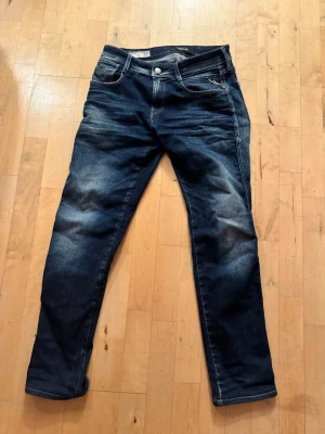 Replay anbass jeans  - Snygga mörkblå jeans från Replay med klassisk femficksdesign och coola slitningar framtill. Jeansen har raka ben och kontrastsömmar samt Replay-logga på bakfickan. Tillverkade i denim med en skön passform. Storlek anbass 30.