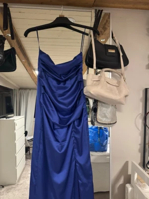 Lång balklänning - Jag säljer nu min balklänning! Använd 3 gånger, inga tecken på användning alls! Klarblå färg, slits vid benet och öppen i ryggen (Går att knyta ryggen på många olika vis.)