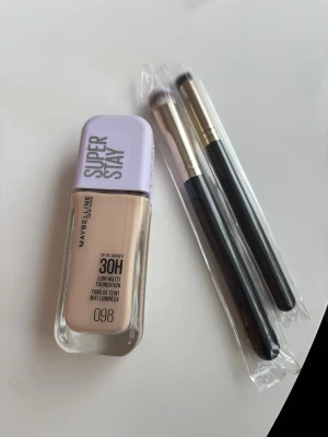 Maybelline Super Stay Foundation 098 - Borstarna är nya och foundationen är använd 1 gång. Inköpt för 1 vecka sen Maybelline Super Stay 30H Lumi Matte Foundation 098.  Inkluderar två sminkborstar.