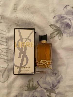 Yves Saint Laurent Libre Eau de Parfum - Säljer en elegant parfym från Yves Saint Laurent, Libre Eau de Parfum. Flaskan är rektangulär i genomskinligt glas med guldiga detaljer och svart asymmetrisk kork. Doften är intensiv och modern, perfekt för dig som vill sticka ut. Kommer med originalkartong.