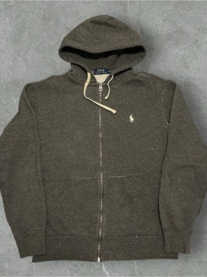 Polo Ralph Lauren Hoodie Grå - 📍Storlek:M  💪🏽Skick:Mycket bra   📐Mått:Längd:63cm:Bred:49:cm:  📎Material:86%Bomull:14%Polyester  📦Skickar alltid inom 24h  💸Köp fler plagg för att få billigare pris  ✅Äkthetsgaranti