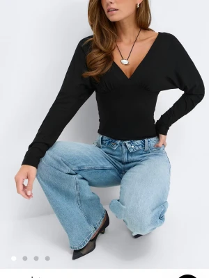 Svart v-ringad långärmad topp - Endast använd en gång annars helt ny och i ett helt nytt skick!!!! Svart långärmad topp med djup v-ringning och figurnära passform. Toppen har en stilren design och är perfekt att matcha med jeans eller kjol. Materialet känns mjukt och stretchigt, vilket gör den bekväm att bära hela dagen.