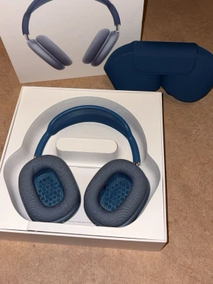 Blå Apple AirPods Max hörlurar - Snygga over-ear hörlurar från Apple i blått aluminium med matchande blå mesh och öronkuddar i tyg. Kommer med Smart Case och originalförpackning. Perfekta för musik, gaming eller film med grym ljudkvalitet och stilren design.