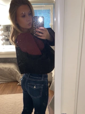 Mörkblå bootcut jeans med kontrastsömmar - Säljer ett par mörkblå bootcut jeans med vita kontrastsömmar och klassisk femficksdesign. Jeansen har knapp- och dragkedjestängning samt fickor med lock och knapp bak. Perfekta för en avslappnad och trendig look.