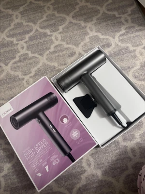 CAPERE High Speed hårfön 2000W - Säljer en helt ny oanvänd CAPERE High Speed hårfön med 2000W effekt. Fönen är grå och har en modern, cylindrisk design med matt finish. Den levereras med ett munstycke och är tillverkad i plast och metall. Perfekt för snabb och effektiv hårtorkning.                           Nypris 1399:-