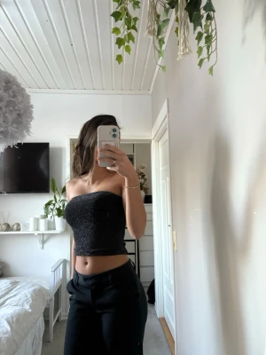 Glittrig svart bandeau tubtopp - Snygg glittrig svart bandeau tubtopp som sitter tight och croppad. Toppen är i storlek S, och i bra skick!