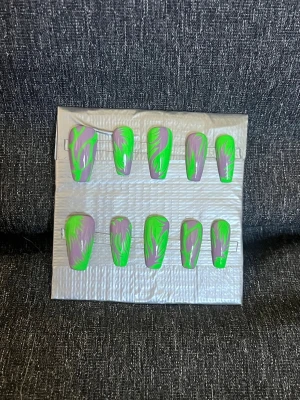 Press-on naglar || Storlek L - Snygga press-on naglar i en cool kombination av neon grön och lila med swirl-mönster. Naglarna har en rak, något avsmalnande form och är perfekta för dig som vill sticka ut. Designen är handmålad för en unik look. Storlek L, Det du får med dig : * Fil och manikyr pinne * nagellim klistermärken * 2 lappar av rengöring för naglar.