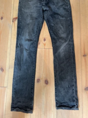 Svarta jeans från Armani Exchange - Snygga svarta jeans från Armani Exchange med klassisk femficksmodell och diskret logga på bakfickan. Jeansen har en smal passform och är tillverkade i ett slitstarkt denimtyg. Perfekta för dig som gillar en stilren och trendig look.