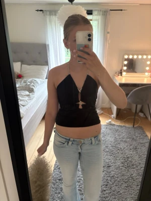Svart croppad halterneck topp - Säljer en svart croppad halterneck topp med glittriga band och snygg cut-out detalj framtill. Toppen är ärmlös och har en tight passform som framhäver figuren. Perfekt för dig som vill sticka ut lite extra. Tröjan är från Bikbok i storlek xs. Fler bilder kan skickas, vid visat intresse🙂