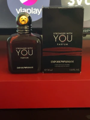 Stronger With You Parfum - Emporio Armani Stronger With You Parfum är en elegant parfym i en mörkbrun glasflaska med silverfärgad spray och svart/guld kork. Flaskan har en stilren, fyrkantig form och rymmer 50 ml. Doften är intensiv och modern, perfekt för dig som vill sticka ut. Köpt på Kicks och det är hälften kvar
