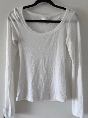 Vit långärmad topp - En enkel och stilren vit långärmad topp.Toppen har en tight passform och är något genomskinlig. Den är perfekt att matcha med jeans eller kjol för en clean look. (Noppror förekommer men går lätt att ta bort)