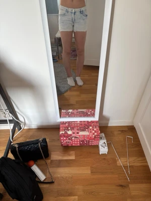 Ljusblå högmidjade jeansshorts - Säljer ett par ljusblå högmidjade jeansshorts med rå kant nertill och klassiska fem fickor. Shortsen har en avslappnad passform och är perfekta för varma dagar. Stängs med dragkedja och knapp framtill.