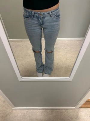 Ljusblå bootcut jeans med hål  - Säljer ett par ljusblå bootcut jeans med slitna hål vid knäna från nelly, säljer för dom har börjat blivit lite små. knappt använda 