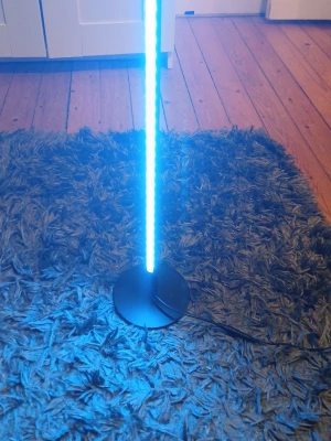 LED hörnlampa med fjärrkontroll - Säljer en svart LED hörnlampa med rund fot och medföljande fjärrkontroll. Lampan har en smal, vertikal design och kan lysa i olika färger. Perfekt för att skapa stämning i rummet med cool belysning. Strömkabel ingår.batteri ingår