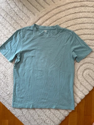 Ljusblåturkos basic t-shirt från 157 - En enkel och stilren tisha. T-shirten har rund halsringning och korta ärmar. Tillverkad i mjuk bomull för en bekväm känsla. Perfekt att matcha med jeans eller shorts. Tror den aldrig blivit använt, så nyskick.