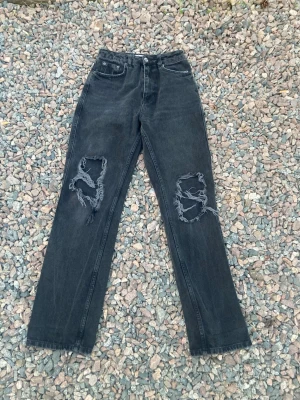 Snygga högmidjade jeans med hål i knäna  - Säljer ett par snygga högmidjade jeans med hål i knäna som har slitningar. Jeansen från NA-KD i storlek 36 och är för långa på mig med ca 1,5-3cm. Dom är välanvända. Jag är ca 1,63cm🤩☺️