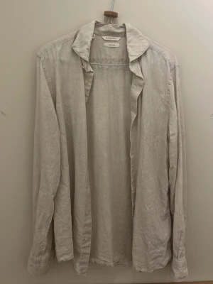 Beige linneskjorta från suit supply  - Säljer en beige skjorta i linne med klassisk krage och långa ärmar. Skjortan har en avslappnad passform och knappar framtill. Från suit supply 