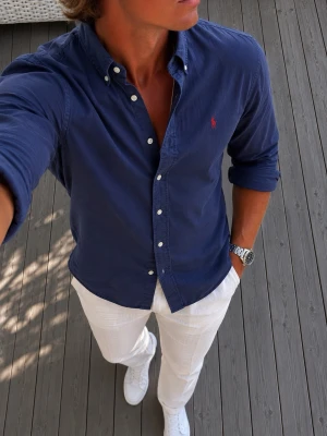 Ralph Lauren slim fit skjorta - Strl XS - Snygg Ralph Lauren mörkblå skjorta med klassisk krage och vita knappar. Skjortan har en liten röd broderad logga på bröstet och är långärmad. Perfekt för en stilren och avslappnad look. Den är mer en S än XS.