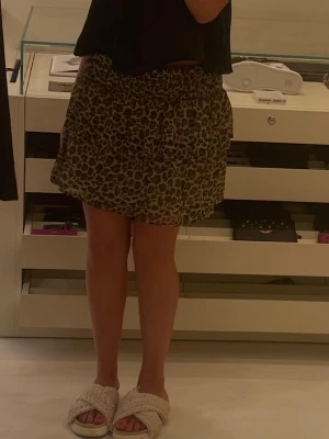 Leopardmönstrad volangkjol - Kort kjol med leopardmönster och bred smock i midjan. Kjolen har dubbla volanger som ger en luftig och trendig look. Perfekt för dig som vill sticka ut med ett djurmönster. Materialet känns lätt och flowy.