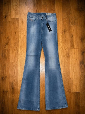 Diesel Skinzee-Flare H jeans – ljusblå – stl W26/L32 (NYA med tags) - Byxorna är helt nya med originaltags kvar.  Märke: Diesel Modell: Skinzee-Flare H Storlek: W26 / L32 Färg: Ljusblå tvätt Material: 93 % bomull, 5 % polyester, 2 % elastan Passform: High waist, super slim flare Skick: Nya med tags  Mått (platt mätta, ca):  * Midja: 34 cm (ca 68 cm runt om) * Innerbenslängd: 82 cm
