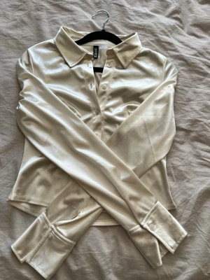 Champagnefärgad satinblus HM - Säljer en champagnefärgad skjorta från HM i glansigt satinmaterial. 