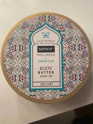 Body Butter - Fräsch body butter från Sence Wellness i doften Emerald med mintolja. Burken rymmer 200 ml och har ett snyggt orientaliskt mönster på locket i färgerna turkos, beige, lila och orange. Perfekt för dig som vill ha återfuktad hud med en fräsch känsla. Helt oanvänd!