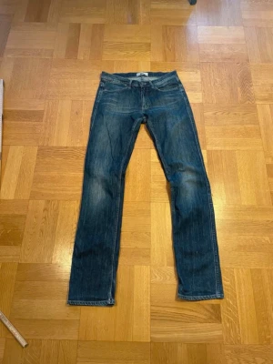 Acne studios Blå raka jeans - Säljer ett par klassiska blå jeans med raka ben och lätt slitna detaljer från Acne. Perfekta till en avslappnad stil och passar till det mesta. Materialet är denim i bomull
