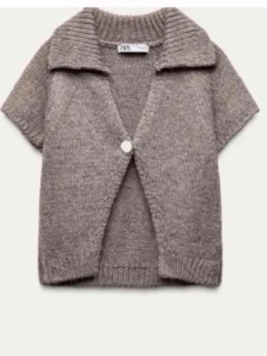 Grå stickad kortärmad kofta Zara - Kortärmad stickad kofta från Zara i gråmelerad ton. Koftan har en bred krage, ribbstickade muddar och stängs med en knapp framtill. Perfekt att slänga över en topp för en avslappnad men snygg look.