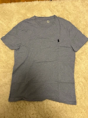 Grå t-shirt från Polo Ralph Lauren - Klassisk grå t-shirt från Polo Ralph Lauren med den ikoniska broderade loggan på bröstet. T-shirten har rund halsringning och korta ärmar. Perfekt basplagg i mjuk bomull som passar till allt.