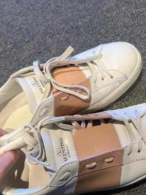 Rosa Valentino sneakers - Snygga sneakers från Valentino i vitt läder. Klassisk låg modell med vita skosnören. Perfekta för dig som vill ha en clean och stilren look med en touch av lyx. Detta är bilder på skorna när jag precis köper dem, de har använts efter det så hör av er för nuvarande bilder, eftersom det finns flera defekter💕💕