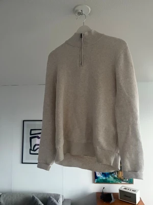 Vit stickad halvzip tröja - Snygg vit stickad tröja med halvzip och hög krage. Tröjan har en avslappnad passform, ribbade muddar vid ärmar och nederkant samt diskret struktur i materialet. Perfekt för lager på lager och enkel att matcha med olika outfits.