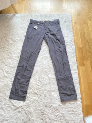 Mörkgrå slim fit chinos Bowery nyskick  - Snygga mörkgrå chinos från Bowery i slim fit-modell. Byxorna har klassisk design med knappgylf och raka ben. Materialet är mjukt och bekvämt, perfekt för en stilren look. Passar dig som gillar en smalare passform och enkel, modern stil. Dem är helt nya inte ens använda dem va fel storlek ny pris är 800kr 