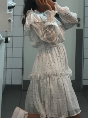 Vit prickig volangklänning - Söt vit klänning med små svarta prickar och volangdetaljer.   
