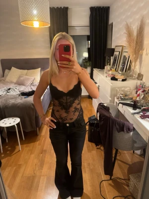 Svart spetsbody med tunna axelband - Säljer en svart body i genomskinlig spets med tunna axelband och vadderade kupor. 