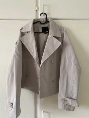  beige trenchcoat  - Superfin trenchcoat från lager 157. Den har några märken på sig som inte är så synliga samt har den man hänger den med gått sönder.