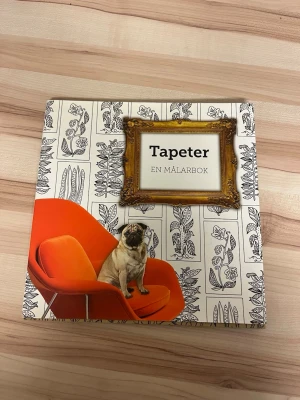 Tapeter: En målarbok - En kreativ målarbok med tapetmönster att färglägga. Omslaget har svartvita illustrationer, en orange retrofåtölj och en mops. Perfekt för dig som gillar inredning och vill slappna av med färgpennor. Utgiven av Tukan förlag. Aldrig använd!