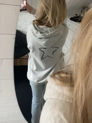 Ljusgrå hoodie med stjärna och text - Ljusgrå hoodie med svart stjärna på ryggen och texten 'AMOUR' på bröstet💫💕 Lite nopprig.