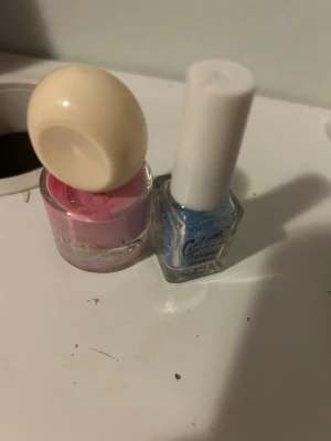 Nagellack rosa & blå glitter - Ett nagellack från Atelier Rouge i en ljusrosa nyans med rund kork och ett blått nagellacks glitter från glam med vit kork. Perfekt för dig som vill variera mellan söt pastell och glittrig look. Båda kommer i glasflaskor med klassisk design.