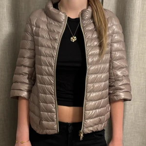 Herno jacka - Snygg beige pufferjacka med glansig finish och trekvartsärmar. Jackan har quiltad design, hög krage och dragkedja framtill. Perfekt för dig som vill ha en lätt och trendig jacka till vår eller höst. Super fin herno jacka i mycket bra skick som passar till typ allt, säljes då den inte kommer till så stor användning längre🥰