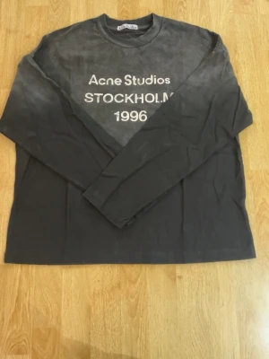 Svart långärmad topp Acne Studios - Cool svart långärmad topp från Acne Studios med tryck 'Acne Studios STOCKHOLM 1996' framtill. Klassisk rund hals och relaxed fit, perfekt till jeans eller kjol. Enkel och stilren design med streetwear-vibe. Har kvitto👍