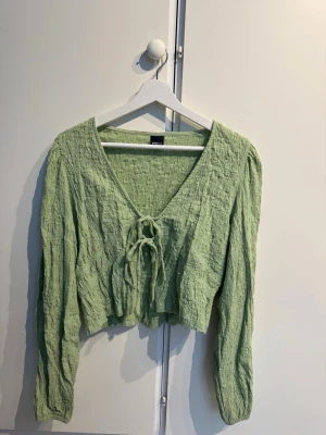 Grön croppad topp med knyt - Så fin topp med knytning fram till, endast använd ca 3 ggr och säljer endast pga att den inte kommer till användning. I storlek L men är som en M!