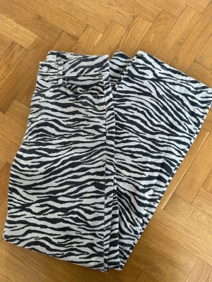 Gina Tricot zebramönstrade raka jeans - Säljer ett par zebramönstrade jeans med raka ben och hög midja. Jeansen är svartvita och har klassisk femficksdesign. Perfekta för dig som vill sticka ut med en cool och trendig look.