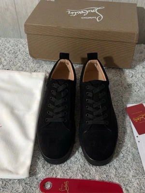 Svarta sneakers från Christian Louboutin 42 - Stilrena svarta sneakers från Christian Louboutin i mocka med matchande svarta skosnören och diskret design. Låg modell med klassisk siluett och beige innerfoder. Perfekta för dig som gillar lyxiga och minimalistiska skor.